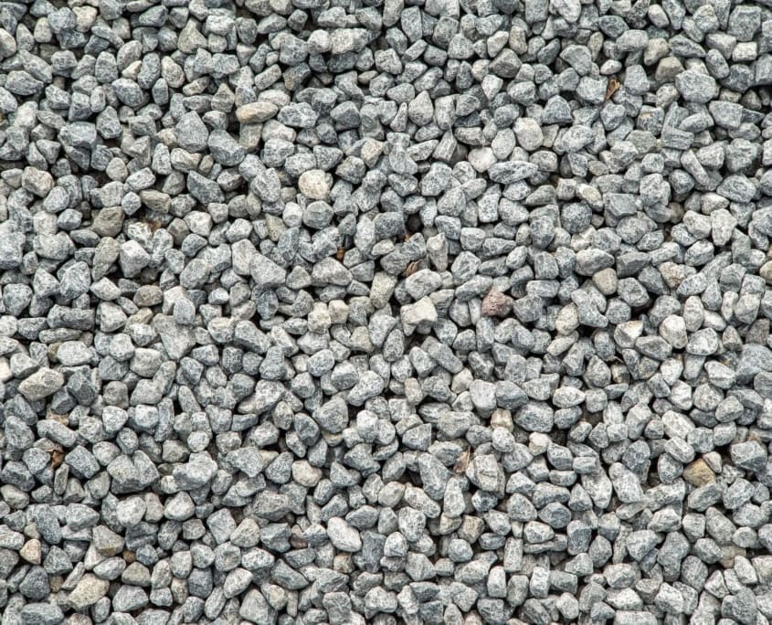 Landscape Design Brisbane A close-up image of a large collection of small gray rocks or gravel, spread evenly across the frame. The rocks vary slightly in size and shape, creating a textured and uniform surface. Live Outdoors